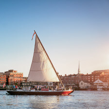 A sailboat glides through Gundalow Harbor in Portsmouth, New Hampshire