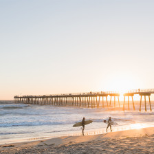Surfers walk near Hermosa Beach Pier in Los Angeles, California