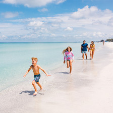A family strolls the shoreline of Coquina Beach in Bradenton, Florida