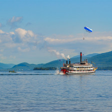 Parasailers glide above a paddlewheeler tour boat on Lake George, New York